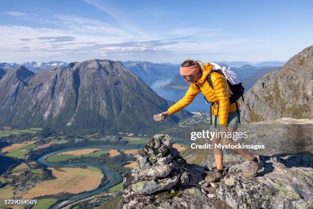 woman hikes in the mountains of norway, she stacks rocks - pile of rocks stock pictures, royalty-free photos & images