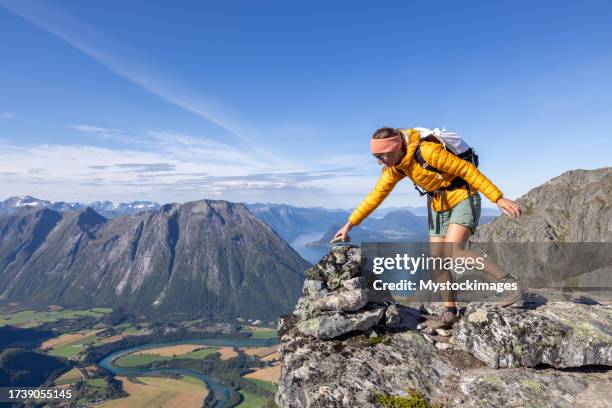 woman hikes in the mountains of norway, she stacks rocks - top that stock pictures, royalty-free photos & images