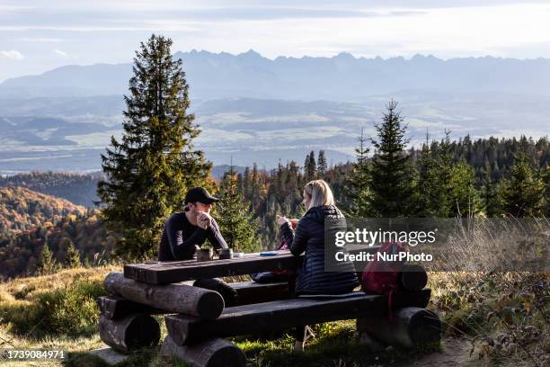 Tourists are seen sitting on a banch on a mountain slope as Autumn colours cover Gorce, the picturesque mountain chain in Western Beskids , Poland on...