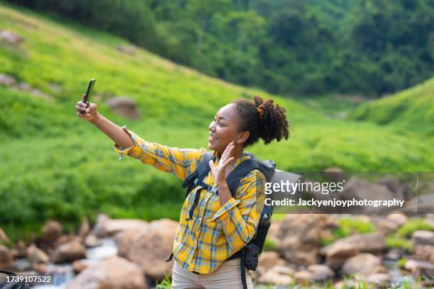 young female influencer live broadcasting on social media with her smartphone while travelling and hiking in the woods. - buch icon stock pictures, royalty-free photos & images