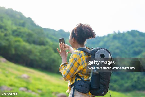 young female influencer live broadcasting on social media with her smartphone while travelling and hiking in the woods. - buch icon stock pictures, royalty-free photos & images