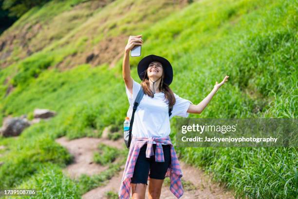 young female influencer live broadcasting on social media with her smartphone while travelling and hiking in the woods. - buch icon stock pictures, royalty-free photos & images