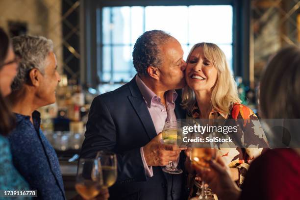 affectionate couple out for drinks with friends - asian couple kissing stockfoto's en -beelden