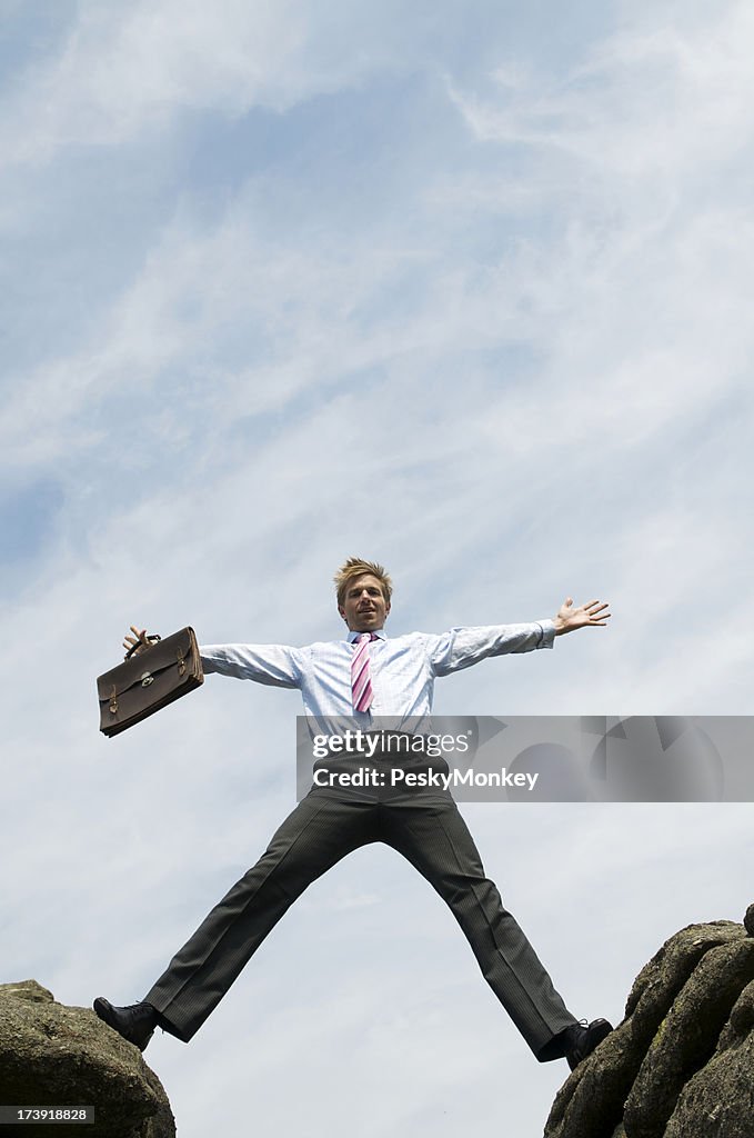 Businessman Straddles the Gap between Rocks