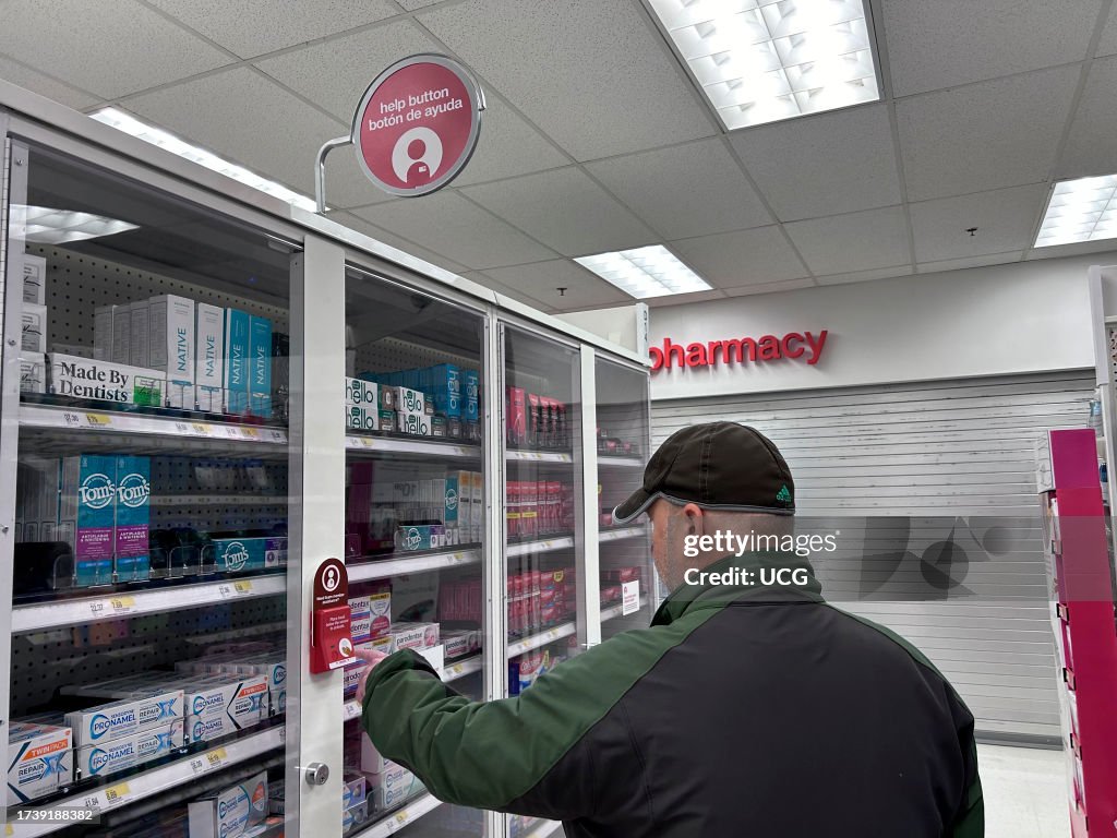 Man pressing button for employee assistance at locked merchandise, CVS store, Queens, New York