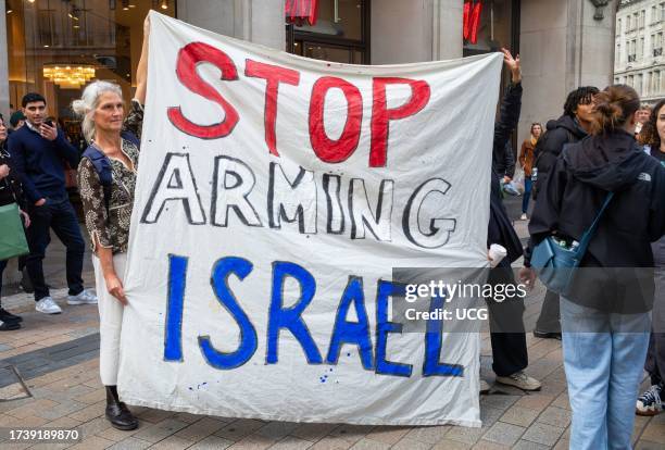 London, UK, A female pro-Palestinian protesters holds a banner stating "Stop Arming Israel" at a demonstration against Israeli attacks on Gaza in...