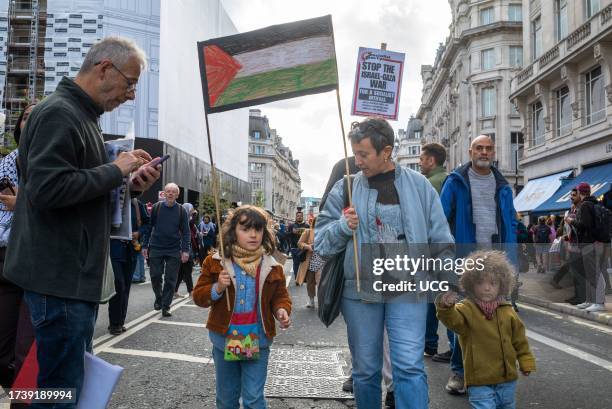 London, UK, A pro-Palestinian mother with her two children holding a Palestinian flag placard at a demonstration against Israeli attacks on Gaza in...