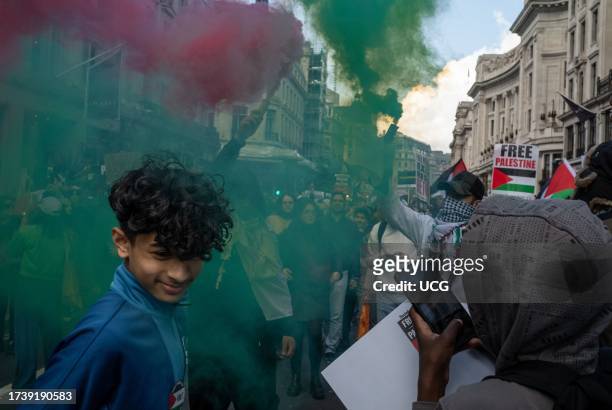 London, UK, A young boy turns away from smoke flares held by Pro-Palestinian protesters in central London, UK at a demonstration against Israeli...