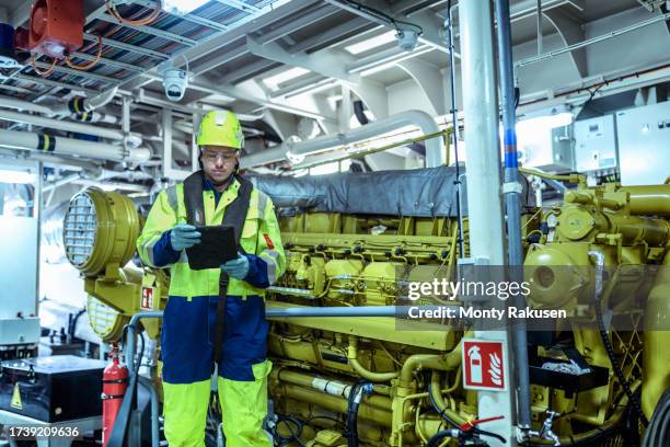 engineer using tablet inspecting ship's engine in engine room - エンジンルーム ストックフォトと画像