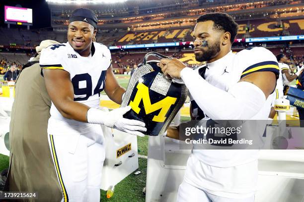 Kris Jenkins and Quinten Johnson of the Michigan Wolverines celebrate with the trophy after the game against the Minnesota Golden Gophers at...