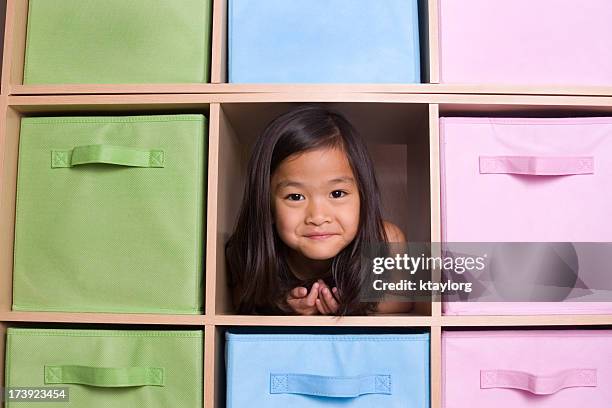 girl peeking through cubed shelving unit - storage compartment stock pictures, royalty-free photos & images