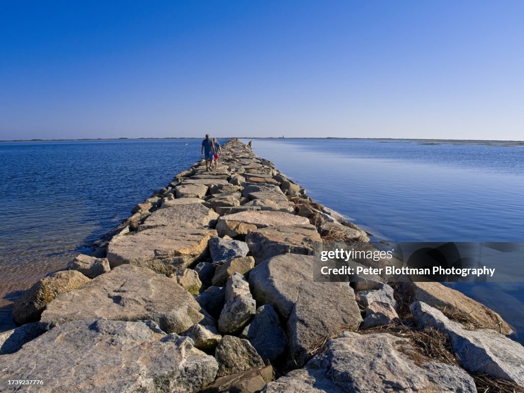 Hikers walk along the Causeway from the mainland towards the Wood End Lighthouse, in Provincetown, Cape Cod, Massachusetts