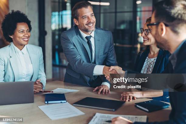 des hommes d’affaires serrant la main de l’autre côté de la table - fusions et acquisitions photos et images de collection