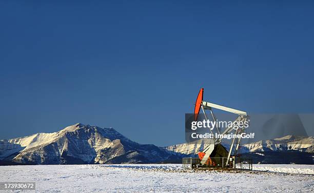 red pumpjack in winter alberta - alberta oil stock pictures, royalty-free photos & images