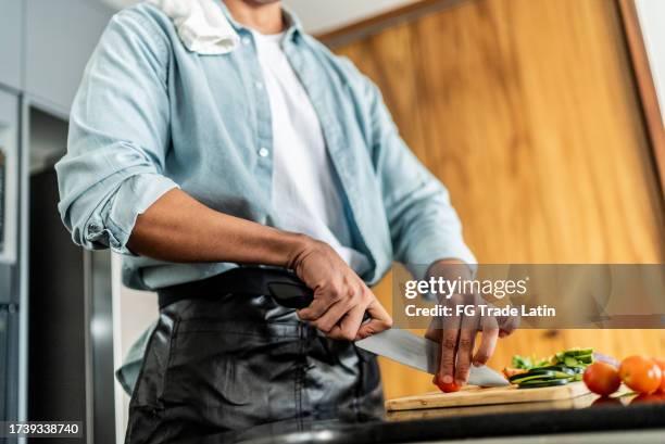mid adult man cutting vegetables in the kitchen counter at homea - knife kitchen stock pictures, royalty-free photos & images