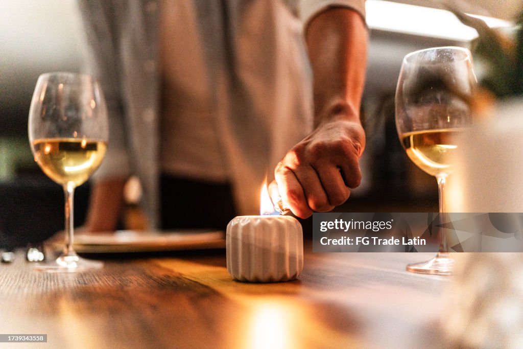 Close-up of a man lighting candle for romantic dinner