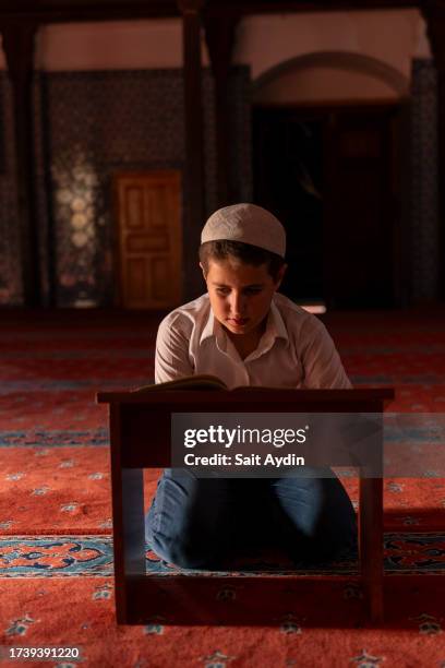 a boy reading the qur'an in a mosque. - 10 11 jaar stockfoto's en -beelden