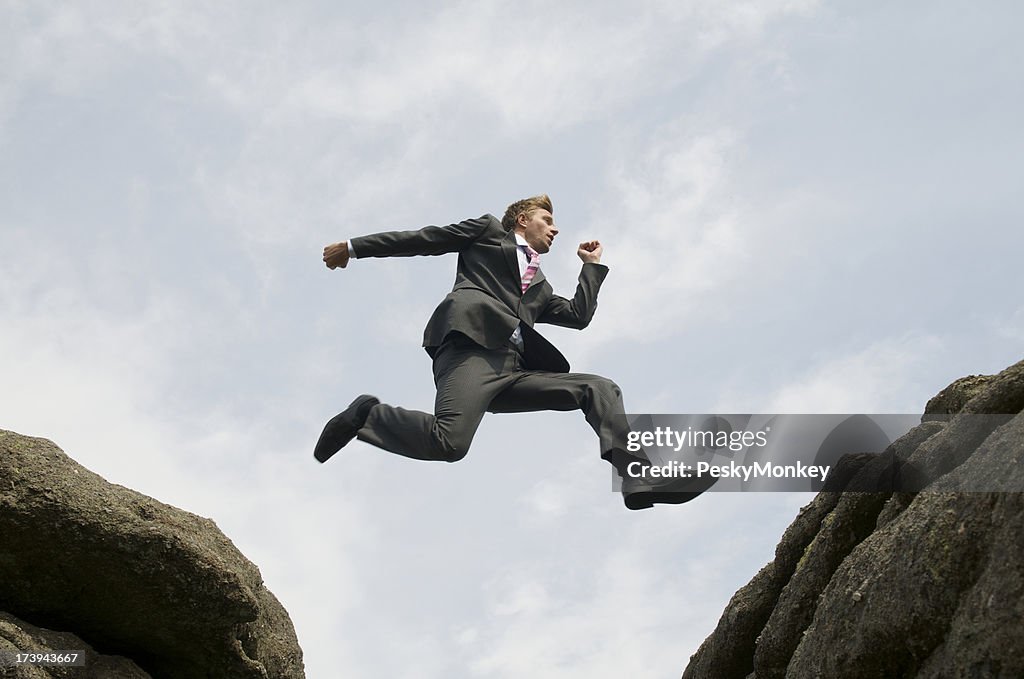 Courageous Businessman Leaping between Rocks