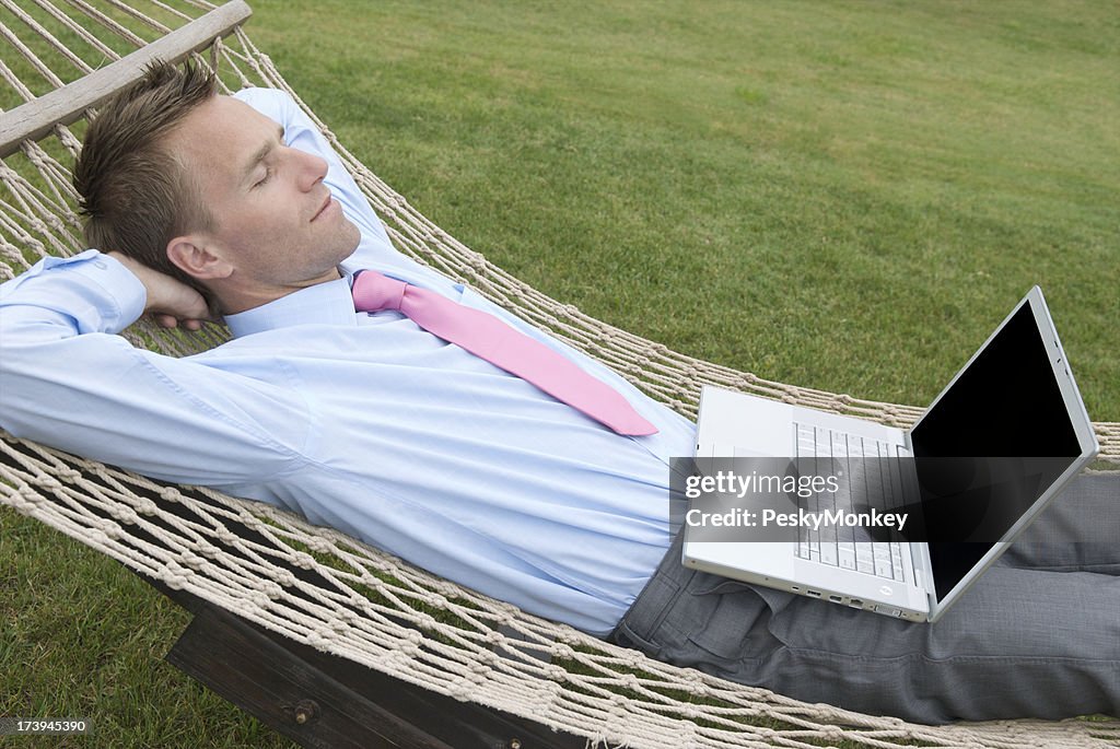 Daydreaming Businessman Relaxing with Laptop in Hammock