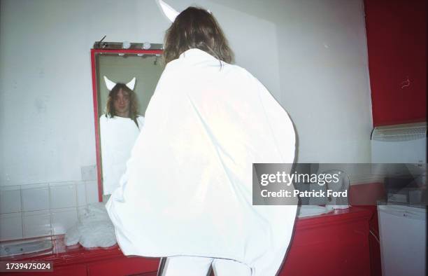 Justin Hawkins of The Darkness looking in a mirror wearing devil horns, backstage at the Astoria London 2003.