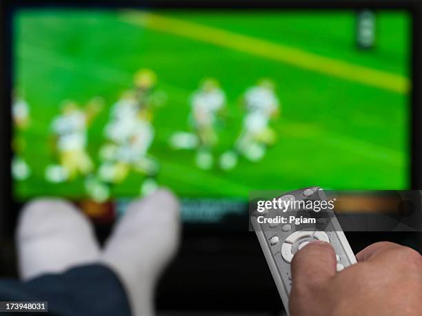 hand holding a tv remote control - american football on screen stockfoto's en -beelden