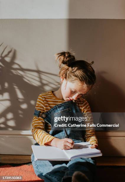 a little girl concentrates as she writes in a notebook - brain thinking goal setting stock pictures, royalty-free photos & images