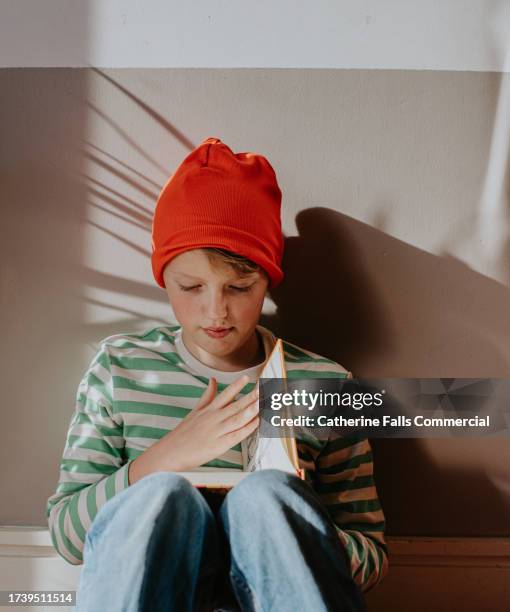 a curious little boy turns the pages of a book - bookshop stock pictures, royalty-free photos & images