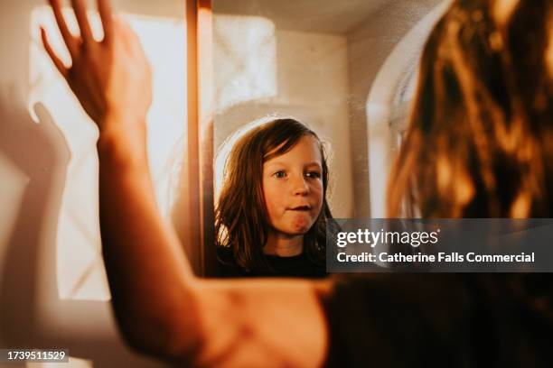 a little girl looks at her reflection in a mirror - girlie room stock pictures, royalty-free photos & images