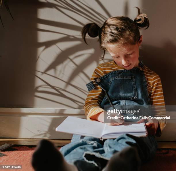 a little girl concentrates as she writes in a notebook - brain thinking goal setting stock pictures, royalty-free photos & images