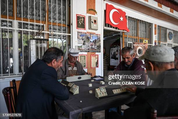 People play the traditional "Okey" game at a cafe next to a Turkish national flag and a portrait of founder of modern Turkey Mustafa Kemal Ataturk in...