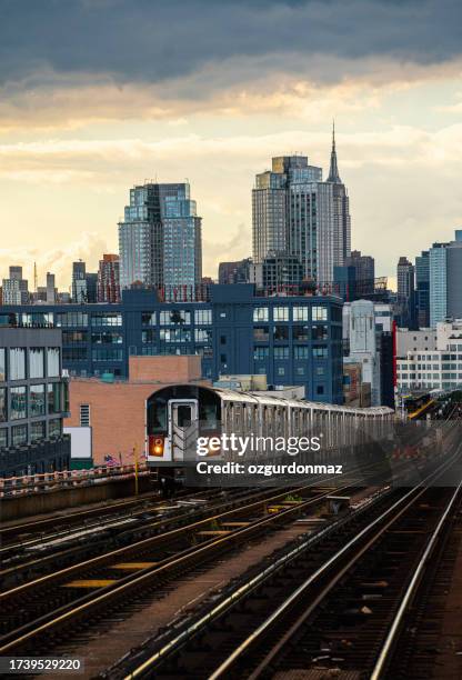 train approaching elevated subway station in queens, new york - new york city subway stock pictures, royalty-free photos & images