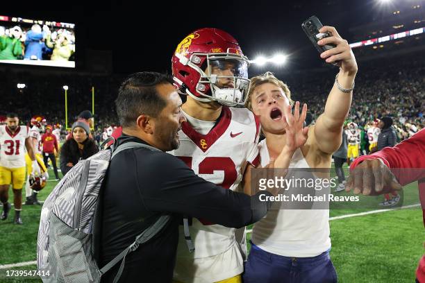 Fan takes a selfie with Caleb Williams of the USC Trojans after the Notre Dame Fighting Irish defeated the USC Trojans and rushed the field at Notre...
