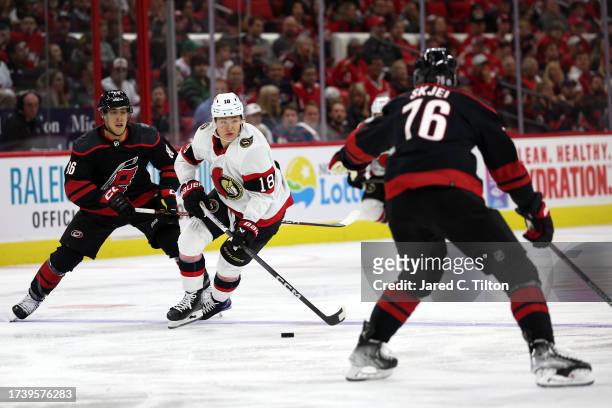 Tim Stutzle of the Ottawa Senators looks to pass as he is defended by Teuvo Teravainen and Brady Skjei of the Carolina Hurricanes during the third...