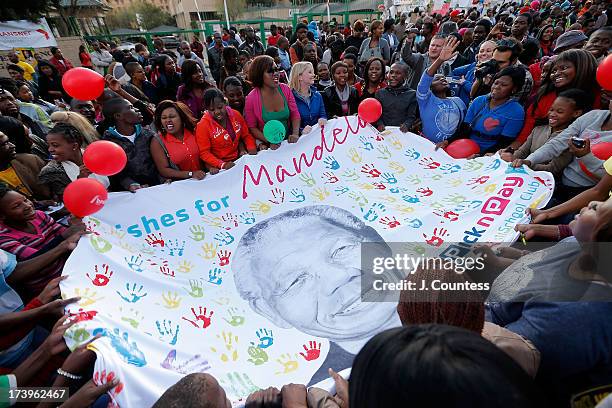 Supporters wave a banner bearing the image of Former South African President Nelson Mandela as crowds are gathered in front of the Medi-Clinic Heart...