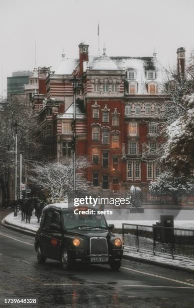 winter wonderland in london: black cab taxi passes through snowy westminster - winter wonderland londen stockfoto's en -beelden