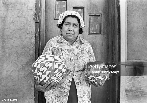 An Acoma Indian Pueblo potter holds two newly fired traditional Acoma Pots, Acoma Pueblo, New Mexico, 1979.