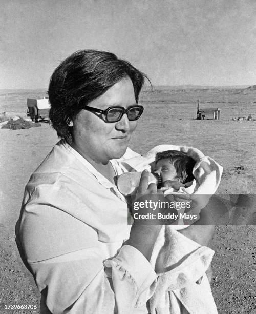Navajo woman feeds her grandchild with a bottle of sheep's milk at a remote sheep camp on the Navajo Indian Reservation, Arizona, 1976.