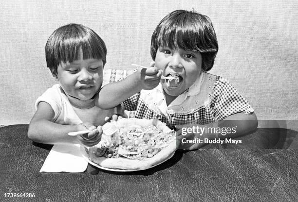 Two young Pueblo Indian children from Jemez Pueblo, chow down on an Indian taco made by their mother, at an arts and crafts fair in Pecos, New...