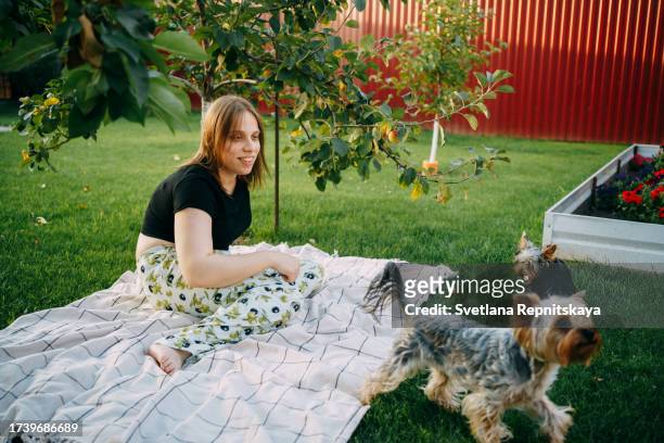 girl with cerebral palsy plays with a yorkshire terrier on a green lawn in the garden - world kindness day stock pictures, royalty-free photos & images