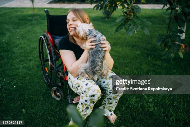 girl with cerebral palsy in a wheelchair plays with dogs in the garden - world kindness day stock pictures, royalty-free photos & images