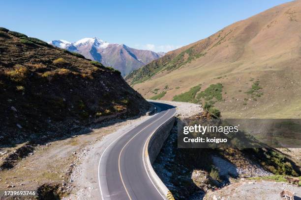 asphalt road at the foot of snow mountain - national road stock pictures, royalty-free photos & images