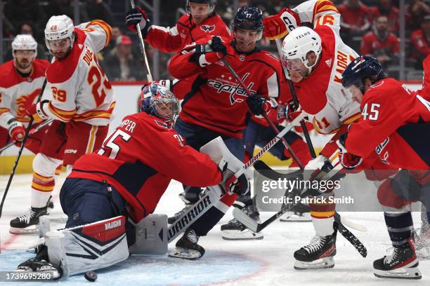 Goalie Darcy Kuemper of the Washington Capitals makes a save as Calgary Flames players crash the net during the first period at Capital One Arena on...