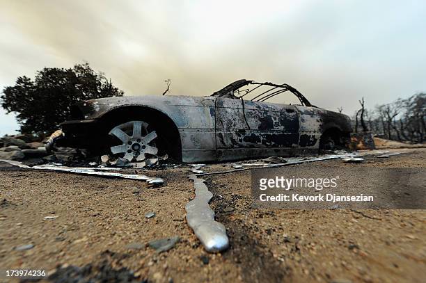 Liquified metal from a burned-out BMW car next to destroyed home is shown after the Mountian Fire scorched the area on July 18, 2013 near Idyllwild,...