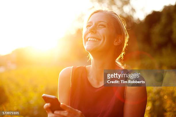young woman using smart phone at sunset - blond hair young woman sunshine stockfoto's en -beelden