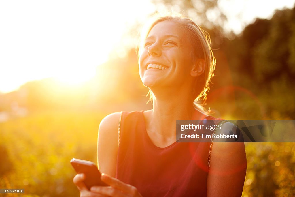 Young woman using smart phone at sunset