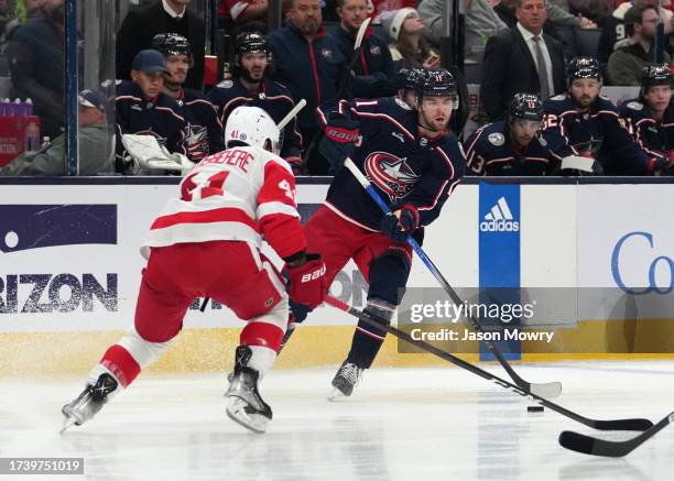 Adam Fantilli of the Columbus Blue Jackets skates with the puck against Shayne Gostisbehere of the Detroit Red Wings at Nationwide Arena on October...