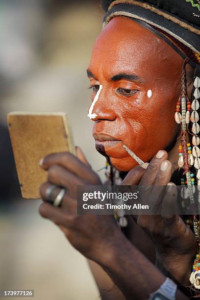 wodaabe man doing makeup in a mirror - gerewol courtship ritual competition stock pictures, royalty-free photos & images