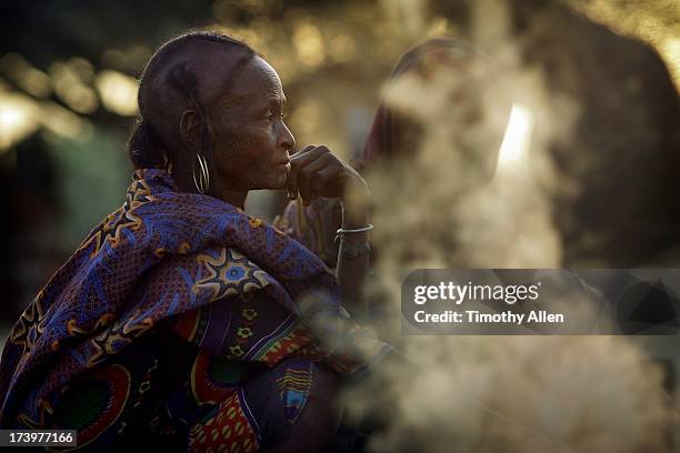 wodaabe woman by smoking fire at dusk - gerewol courtship ritual competition stock pictures, royalty-free photos & images