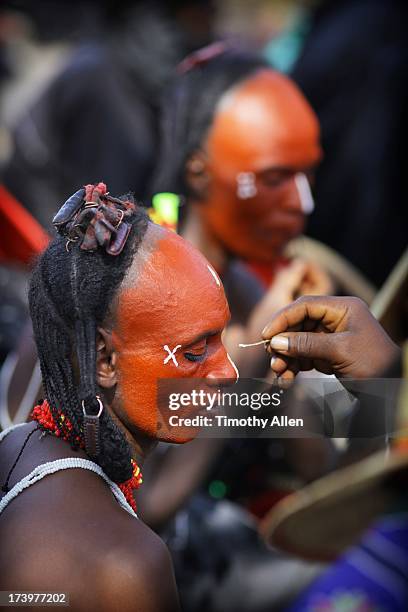 a wodaabe man with red face has makeup done - gerewol courtship ritual competition stock pictures, royalty-free photos & images