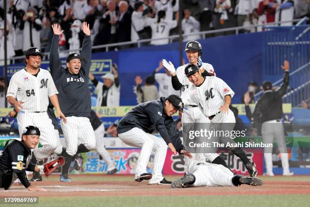 Hiromi Oka of the Chiba Lotte Marines is congratulated by his teammates after scoring a run to end the game by the RBI double of Hisanori Yasuda in...